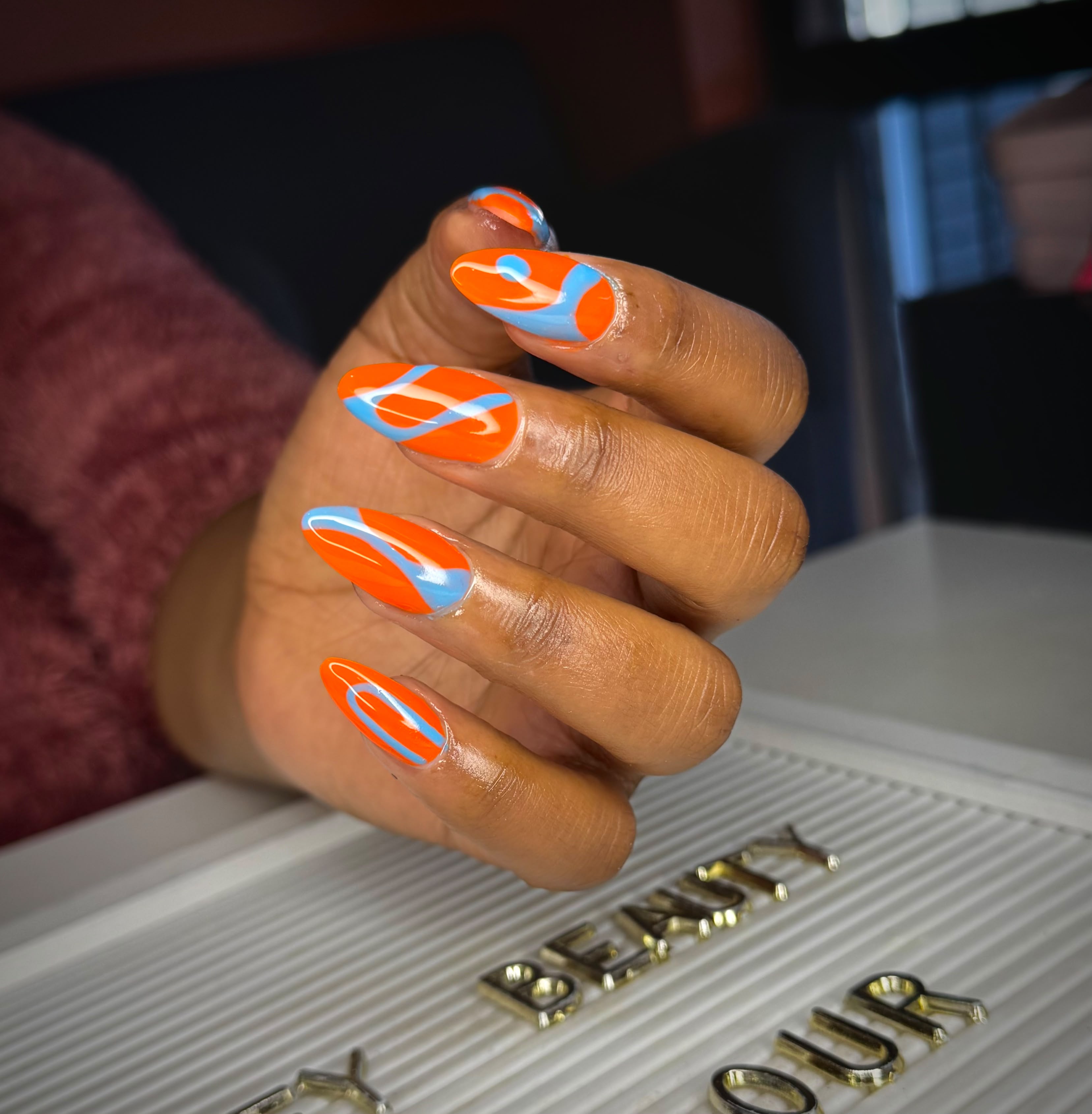 Orange swirl nail art on long nails